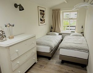 Tweede slaapkamer in Westhoek, Schiermonnikoog, met twee eenpersoonsbedden en houten vloeren.