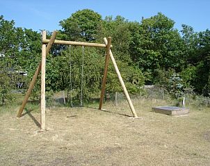 Speelplaats met schommel bij Duinrust vakantiehuis op Schiermonnikoog, omgeven door natuur.
