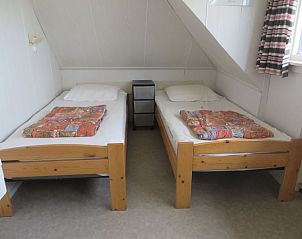 Slaapkamer in Zeerust vakantiehuis op Schiermonnikoog met twee eenpersoonsbedden onder een schuin dak.