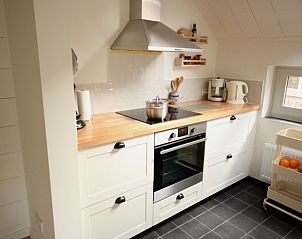 Moderne keuken in Opa's huis, vakantieaccommodatie Schiermonnikoog, met houten aanrecht en witte kasten.