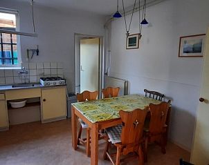 Eetkamer van Stachouwer vakantiehuis, Schiermonnikoog, met landelijke keuken en houten tafel voor gezellige maaltijden.