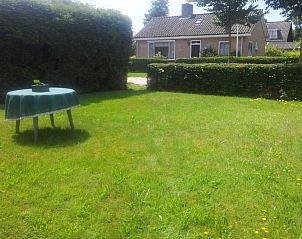 Zonnige tuin met tafel bij Stachouwer vakantiehuis, Schiermonnikoog, ideaal voor buitenactiviteiten op de Waddeneilanden.