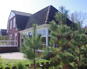 Zijaanzicht van Twa Blomkes vakantiehuis op Schiermonnikoog, omgeven door groene natuur.