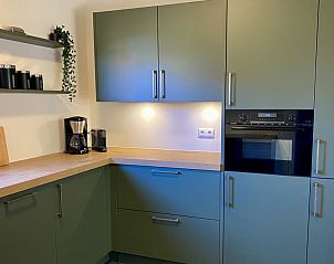 Moderne keuken in Twa Blomkes vakantiehuis op Schiermonnikoog, met stijlvolle groene kasten.