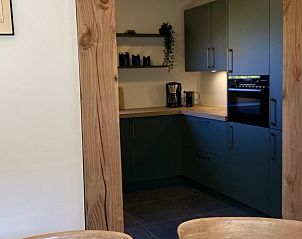 Doorkijk naar de keuken van Twa Blomkes vakantiehuis op Schiermonnikoog, met rustieke houten details.