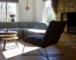 Gezellige woonkamer in Twa Blomkes vakantiehuis op Schiermonnikoog, met open haard en comfortabele zitplaatsen.