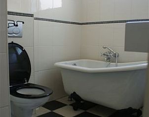 Stijlvolle badkamer in Twa Blomkes vakantiehuis op Schiermonnikoog met vrijstaand bad en zwart-witte tegels.