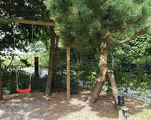 Speelse tuin van Hannekommen vakantiehuis met schommel, omgeven door bomen op Schiermonnikoog, Waddeneilanden.