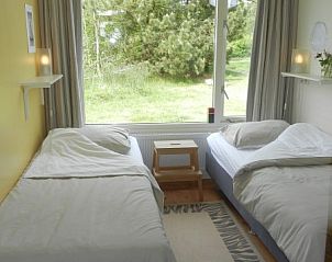 Slaapkamer met twee bedden in Buutvrij vakantiehuis op Schiermonnikoog met uitzicht op tuin.