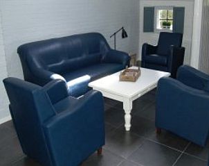 Comfortabele woonkamer in vakantiehuis Henny, Schiermonnikoog, met luxe leren banken voor ontspanning op de Waddeneilanden.