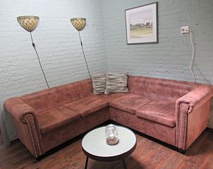 Gezellige zithoek in vakantiehuis Adje op Schiermonnikoog met comfortabele bank en sfeerverlichting.