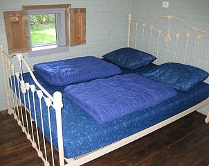 Slaapkamer in vakantiehuis Adje op Schiermonnikoog met comfortabel bed en houten luiken.