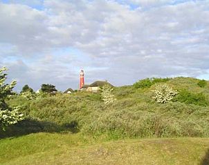 Omgeving van Casa Maris op Schiermonnikoog met vuurtoren en groene duinen in de verte.