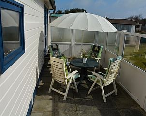 Terrasse des CORIMAR Chalets, Ballum, Ameland mit Sonnenschirm und Tisch.